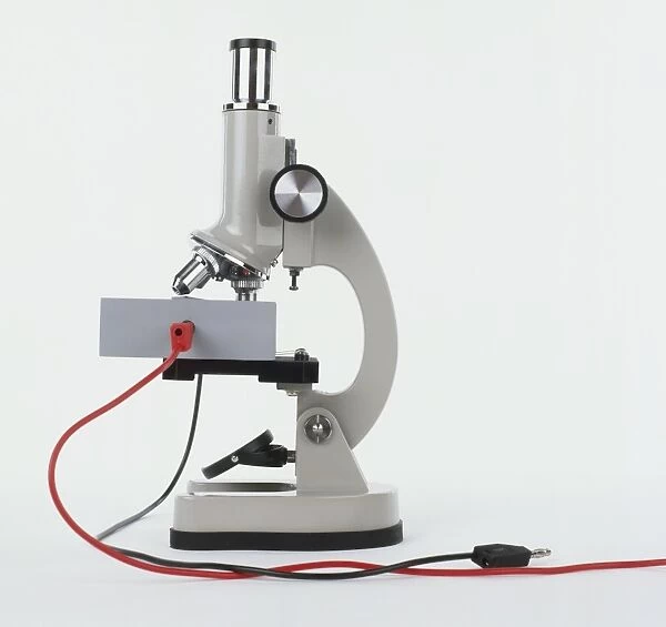 Side view of a microscope with red and black wires