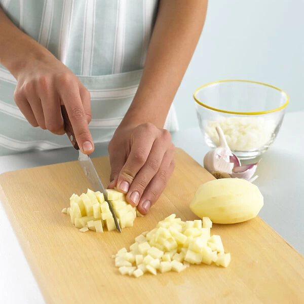 Woman dicing raw potato on chopping board