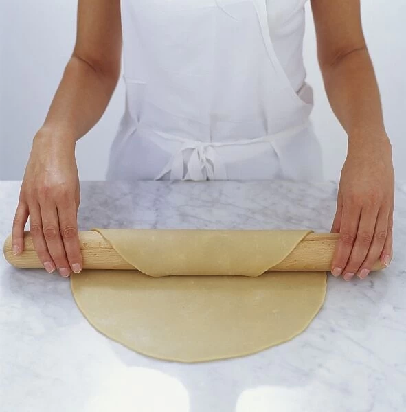 Woman draping pastry over rolling pin