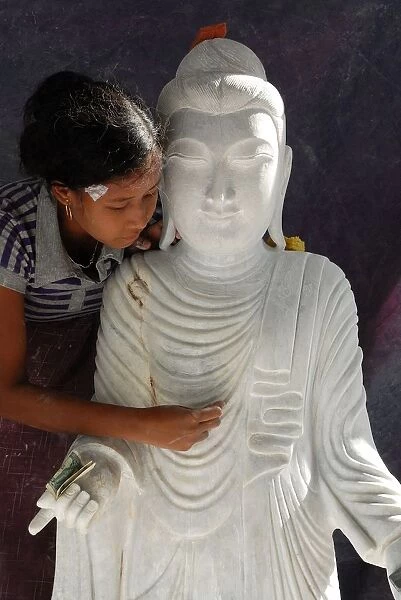 Woman polishing a marble Buddha statue