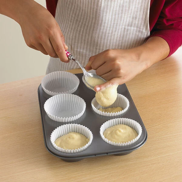 Woman spooning cake batter into cupcake cases