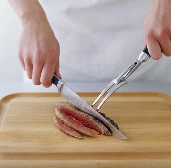 Womans hands carving rare-cooked duck breast on chopping board, close-up