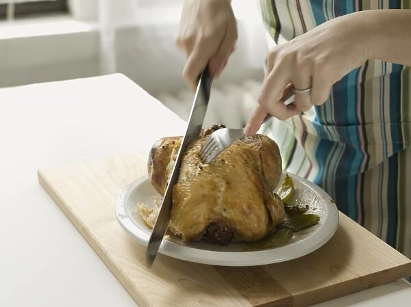 Womans hands carving roast chicken, close-up