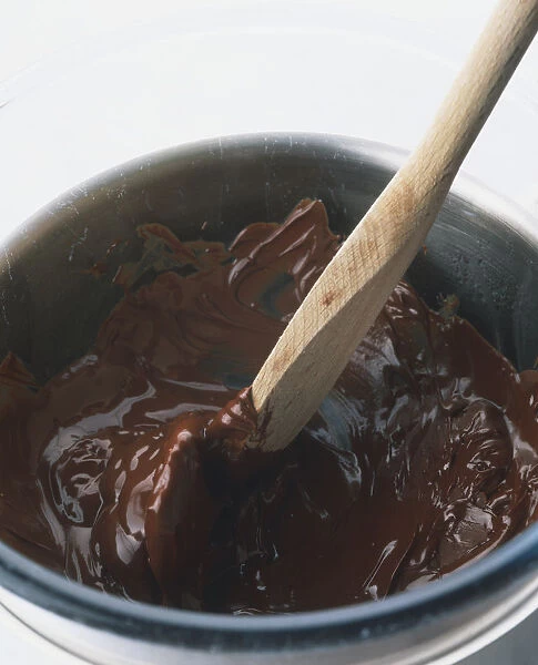 Wooden spoon stirring molten chocolate