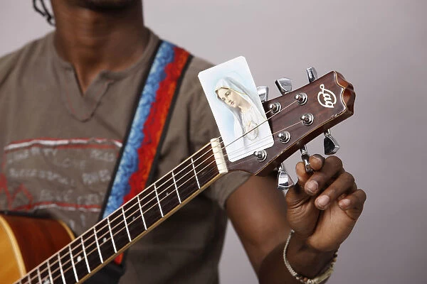 Young Christian man tuning a guitar
