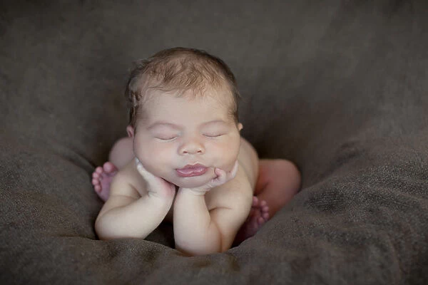 Newborn baby, five days, asleep with head propped up on hands