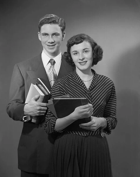 Young man and woman holding books, portrait