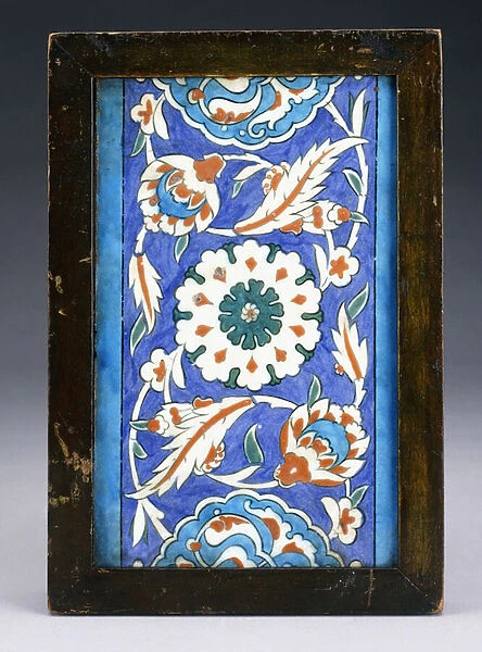 An Iznik border tile, with a central flowerhead between scrolling palmette and leafy vine