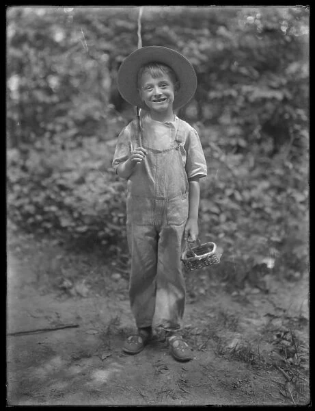 William Gray Hassler in straw hat and overalls, carrying fishing pole