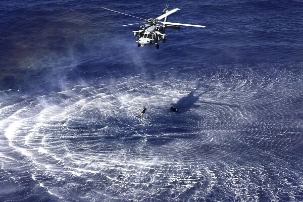 An MH-60S Seahawk lowers a rescue swimmer into the water