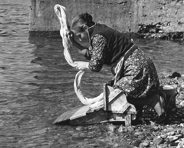 Woman washing clothes in a river, Portugal, 1973