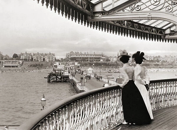 Two women look down on Clacton pier at Clacton-on-Sea, Essex, England towards the end of the 19th century. After a print by an unknown photographer