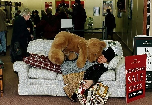 Ewan MacLeod lying on sofa with giant teddy bear supermarket basket of Christmas shopping