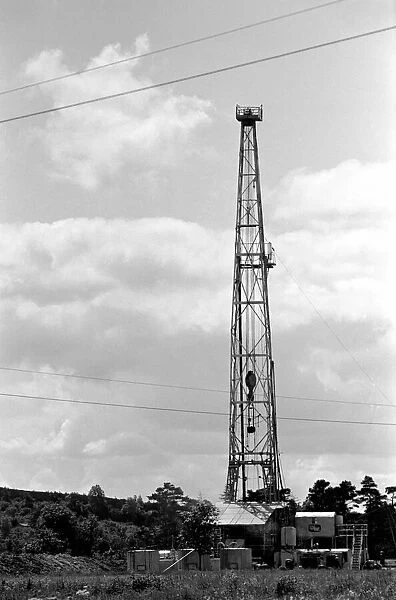Oil well drilling for oil in Ireland. A farmhouse on the roadside has a grand stand view