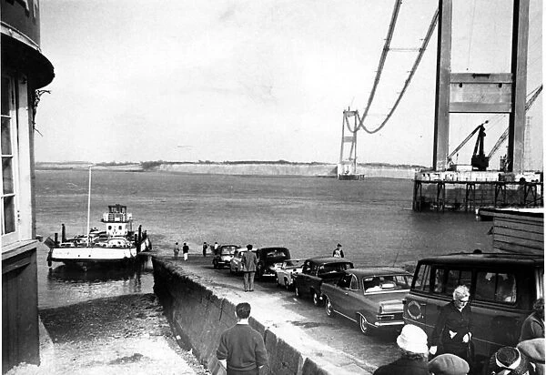 Severn Bridge - Cars queue to use the Aust Severn ferry with the Severn Bridge towering