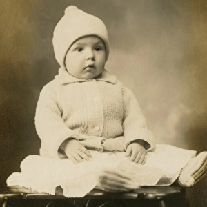 Adorable baby in woollen hat and cardigan