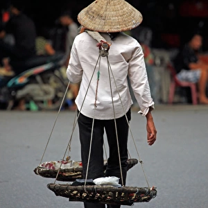Person carrying traditional baskets in Hanoi, Vietnam