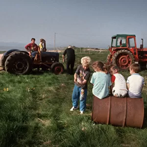Young children play and men work on tractors - Askam, Cumbria