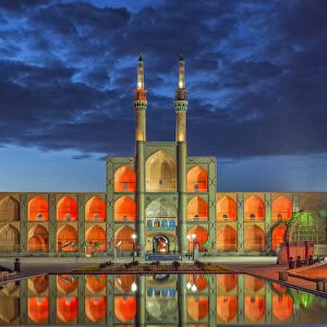 Amir Chaqmaq complex facade illuminated at sunrise and reflecting in a pond, Yazd