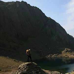 A hiker looks across the still waters of Llyn Du r Arddu, one of Waless highest lakes