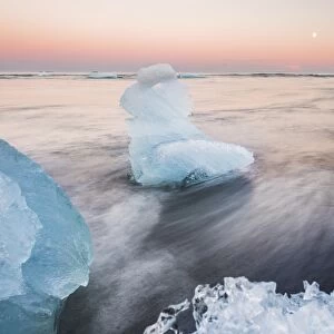 Icebergs at sunset on Jokulsarlon Beach, a black volcanic sand beach in South East Iceland