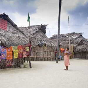 Molas hanging up for sale outside thatched houses, Isla Tigre, San Blas Islands