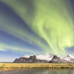 Northern lights (aurora borealis) on snowy peaks and icy sea along Mefjorden seen