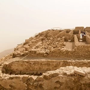 Tourists at Masada fortress ruins, air thick with desert sand, UNESCO World Heritage Site