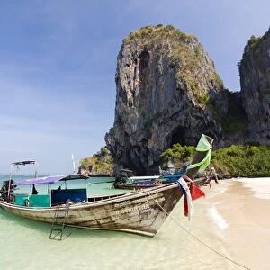 Traditional Longtail boats moored by Phra Nanag Beach with limestone cliffs in the background