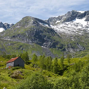 A wooden barn on a hillside below the Frudalsbreen Glacier, Vestlandet, Norway
