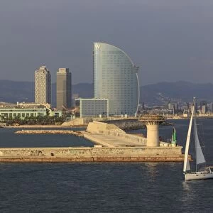 Yacht sails past La Barceloneta and the waterfront, Port Olimpic in distance, late afternoon, Barcelona, Catalonia, Spain, Europe