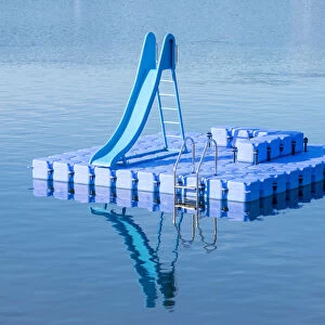 Blue dock with water slide floating in blue lake, Hamburg Stadtpark, Hamburg, Germany