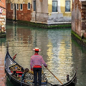 Gondolier with hat on gondola boat in a water canal, Venice, Veneto, Italy