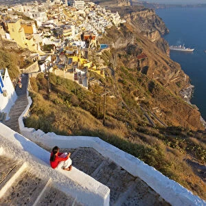 Greece, The Cyclades, Santorini (Thira), Fira, Woman sitting on wall in town (MR)