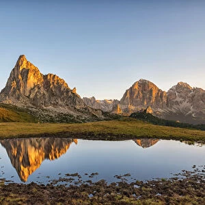 Gusela mountain at sunrise reflected in small lake, Giau Pass, Dolomites, Veneto, Italy