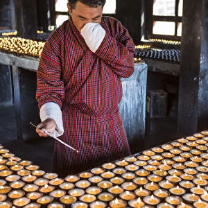 A man lighting candles in a shrine in Jambey Lhakhang, Jakar, Bumthang District, Bhutan