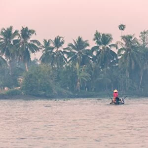 Vietnam, Mekong Delta, Can Tho. Vietnamese woman on small boat, on the Mekong delta at sunset