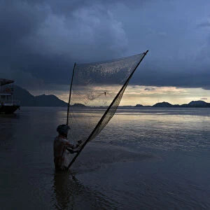 A man catches fish at the banks of the Brahmaputra river in Guwahati