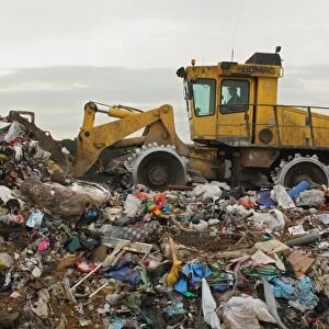 Compactor moving rubbish on landfill tip, Dorset, England, February