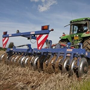 Tractor with disc harrows, harrowing stubble field, Sussex, England, september