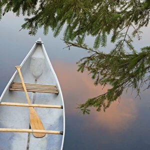 Canada, Quebec, Eastman. Canoe on lake at sunset