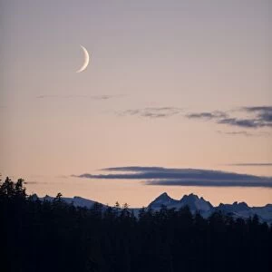 USA, Alaska, Tongass National Forest, Crescent moon sets above mountain peaks of