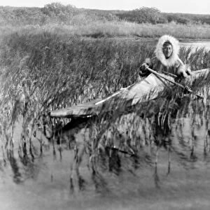 ALASKA: ESKIMO, c1929. An Eskimo muskrat hunter paddling through the marsh, Kotzebue, Alaska