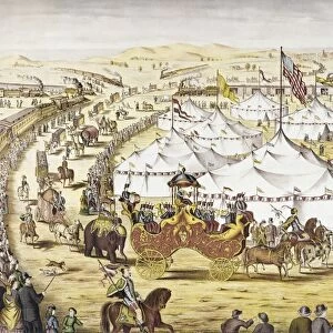 AMERICAN CIRCUS, c1874. The Grand Layout. Circus parade around tents with a crowd watching alongside a railroad train. American lithograph, c1874