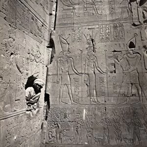 EGYPT: MEDINET HABU. A young man looking through a hole in a wall covered with