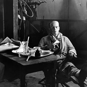FRANKENSTEIN, 1931. Boris Karloff still in makeup as the Monster, having lunch on the stage set of Frankenstein, 1931