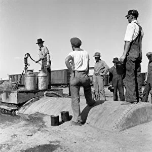 MIGRANT WORKERS, 1939. Group of migrant workers waiting to get water at a camp in Tulelake