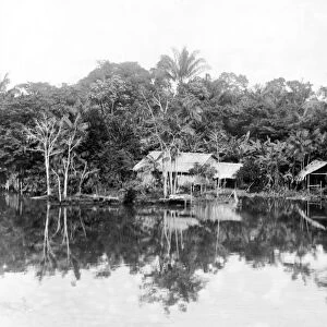 NATIVE BRAZILIANS. Native Brazilian huts in a clearing on a river bank in Brazil