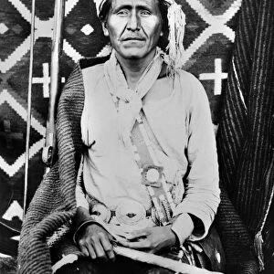 A Navajo shaman posed in front of a woven blanket. Photographed by John K. Hillers, c1880