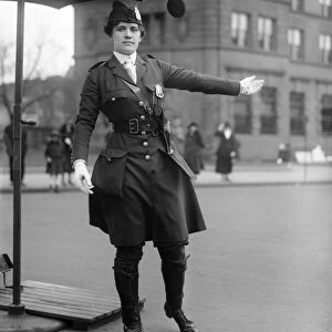 TRAFFIC COP, 1918. A female traffic cop directing traffic under an umbrella stand